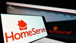 Smartphone with logo of British repairs company HomeServe plc on screen in front of business website. Focus on center-left of phone display.