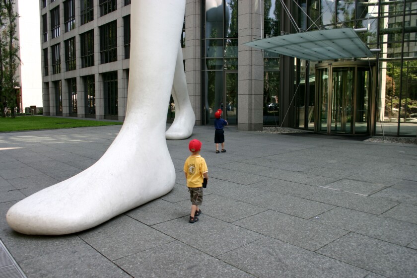 kids impressed by big foot Walking Man in front of Muenchener Rueckversicherung Munich Re Bavaria Germany