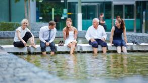 Happy business people talking during break in summer with their feet in water