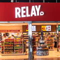 The storefront of a Relay press and convenience store, displaying magazines, snacks and souvenirs, at Barcelona Airport.