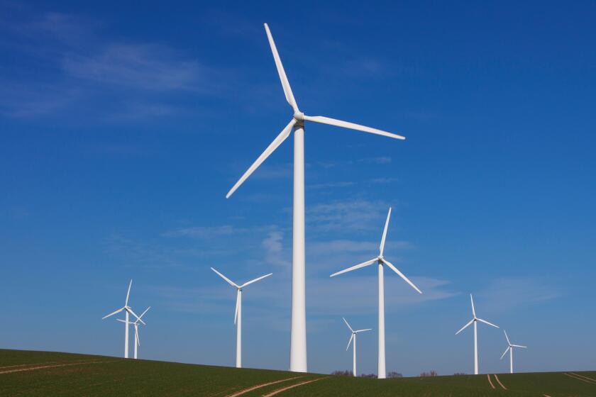 Wind turbines at windfarm in field against blue sky