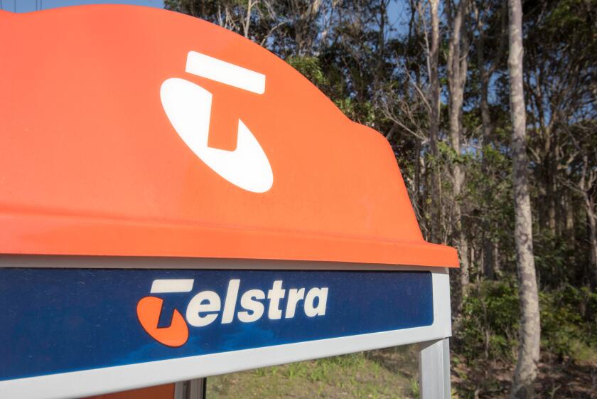The distinctive orange top of a traditional Telstra public phone booth on a footpath in a rural village now almost redundant due to mobile phones
