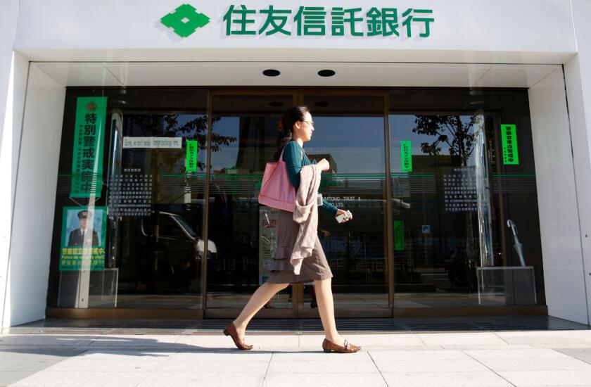A woman walks past a branch of Sumitomo Trust and Banking Co in Tokyo November 6, 2009. Sumitomo Trust and Banking Co and Chuo Mitsui Trust Holdings Inc said they plan to merge, creating Japan's largest trust bank with scale to better compete in a crowded