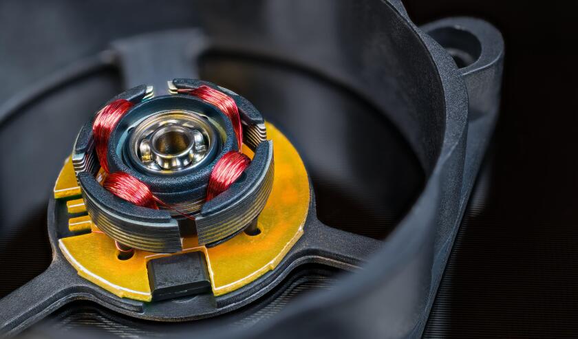Electric motor rotor with permanent magnet, copper wire inductors and metal ball bearing. Disassembled computer fan with integrated Hall-effect sensor.