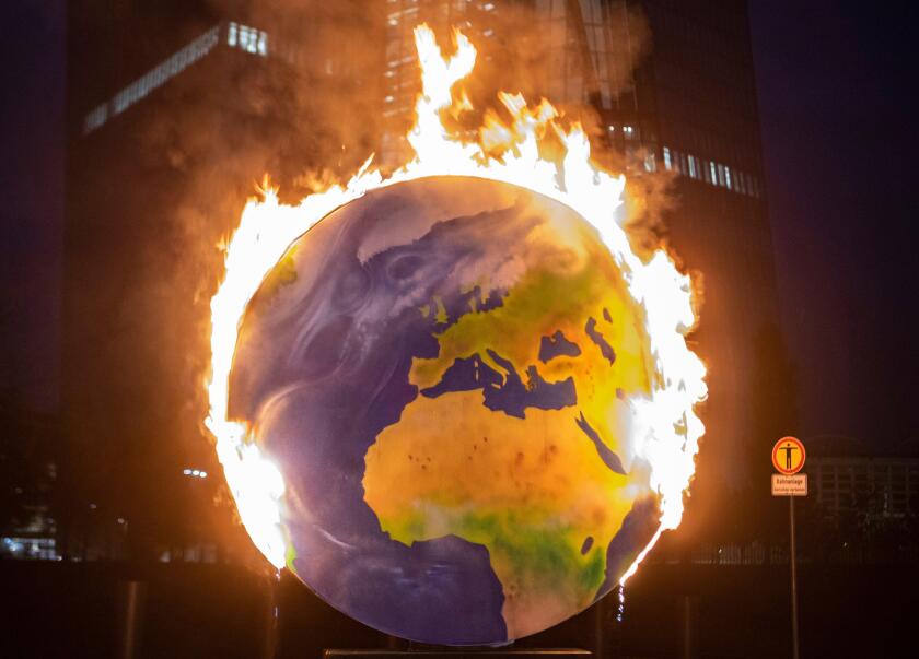 21 October 2020, Hessen, Frankfurt/Main: With a burning globe, activists of the group "Das Koalakollektiv" demonstrate in front of the European Central Bank (ECB) in Frankfurt against the climate policy of the financial institution. The activists demand t