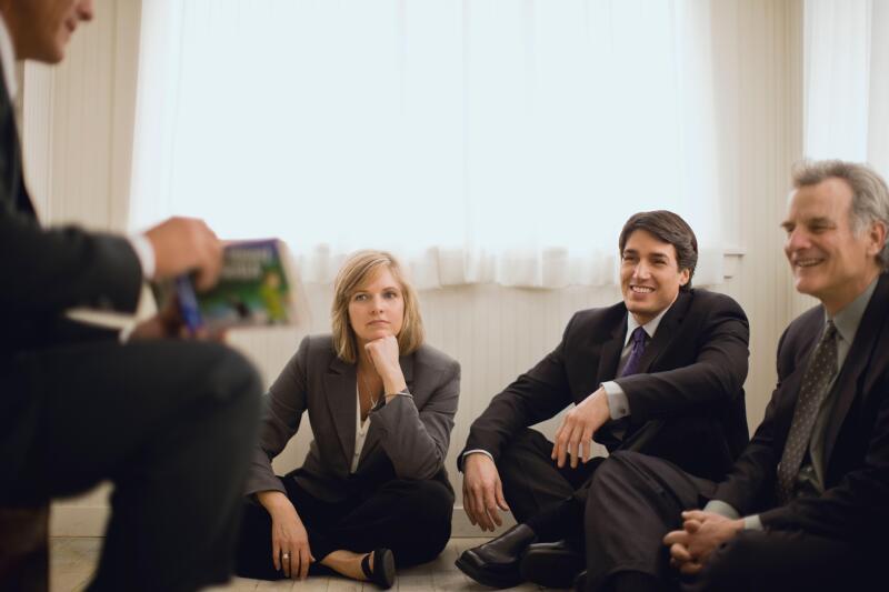 Businesspeople sitting around businessman telling story