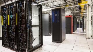 Racks of servers aligned in rows in a large computer server farm.