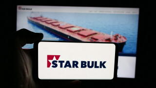 Stuttgart, Germany - 12-16-2025: Person holding cellphone with logo of shipping company Star Bulk Carriers Corp. on screen in front of webpage.