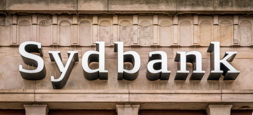 Sign of the danish sydbank in white letters on a brownish facade in Svendborg, Denmark, July 10, 2019