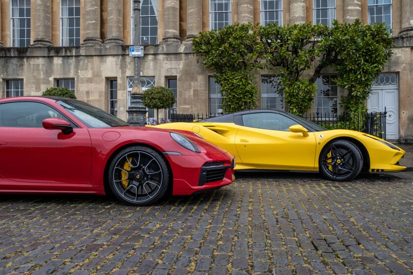 A bright yellow Ferrari and a red Porsche on a cobbled English street