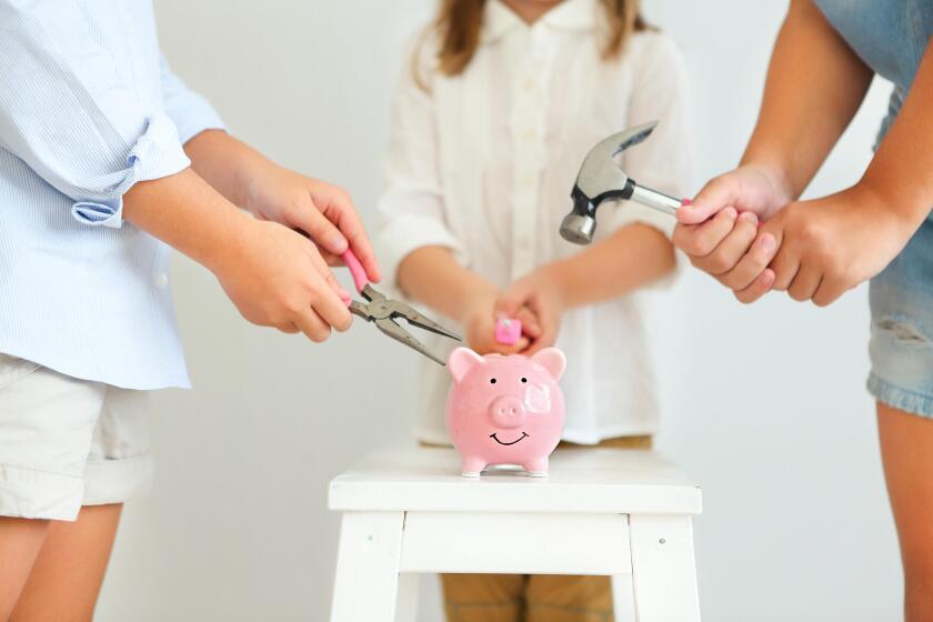 Kids with screwdriver, pliers and hammer by the pink pig piggy bank on a white background