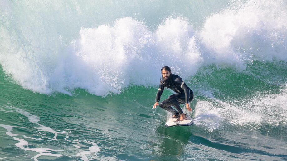 A male surfer riding a wave on a surfboard near Huntington Beach