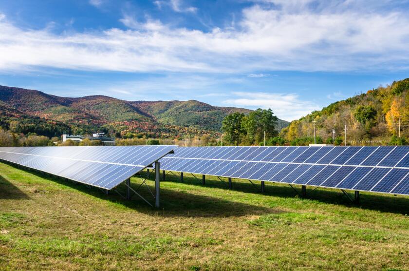 Rows of solar panels in a field in the Mountains on a sunny autumn day