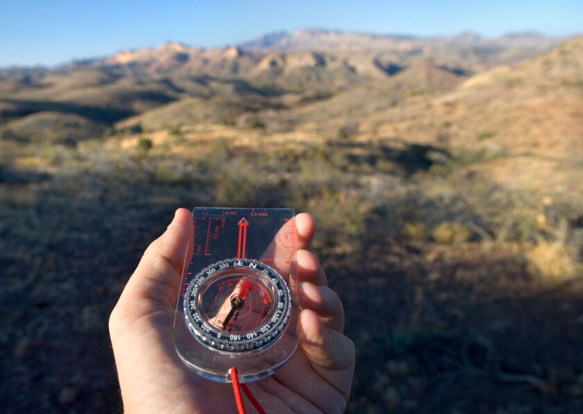 Looking at a hiking compass while hiking.