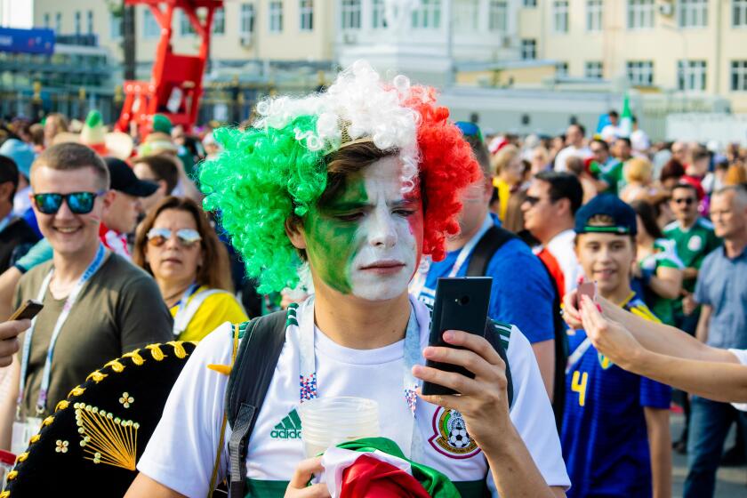 Serious male Mexican football fan with frizzy green, white and red wig checks mobile phone - FIFA World Cup Russia 2018 Mexico v Sweden, Ekaterinburg