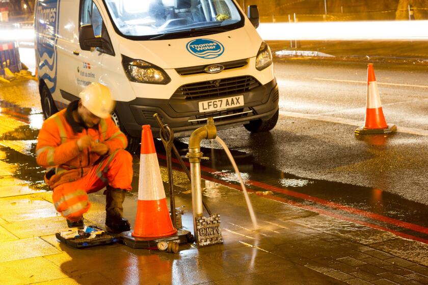 watermain burst repaired by Thames water engineer at road side, England