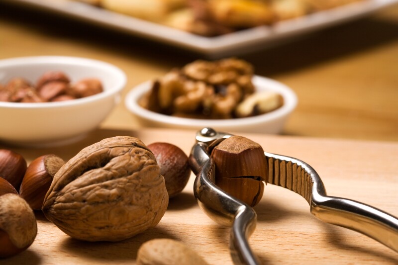 close up of nutcracker, hazelnuts, walnuts, almonds, baked cookies in background. Image shot 10/2008. Exact date unknown.