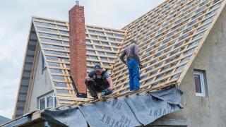 Male carpenters repair the roof of the house.