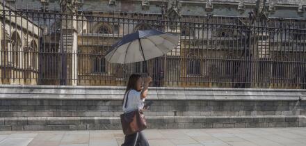 UK Heatwave: 22 June 2026  A pedestrian in Westminster shelters with an umbrella on hot sweltering day in London