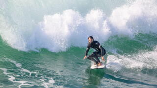 A male surfer riding a wave on a surfboard near Huntington Beach