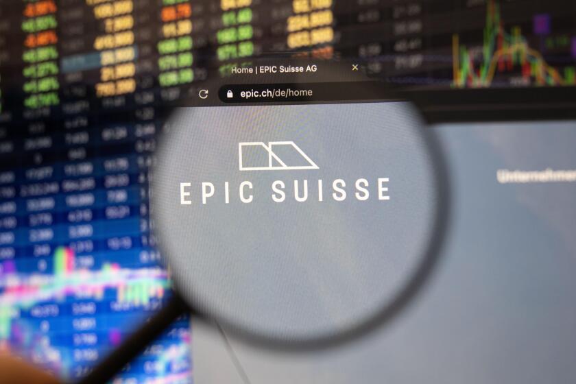 Epic Suisse company logo on a website with blurry stock market developments in the background, seen on a computer screen through a magnifying glass
