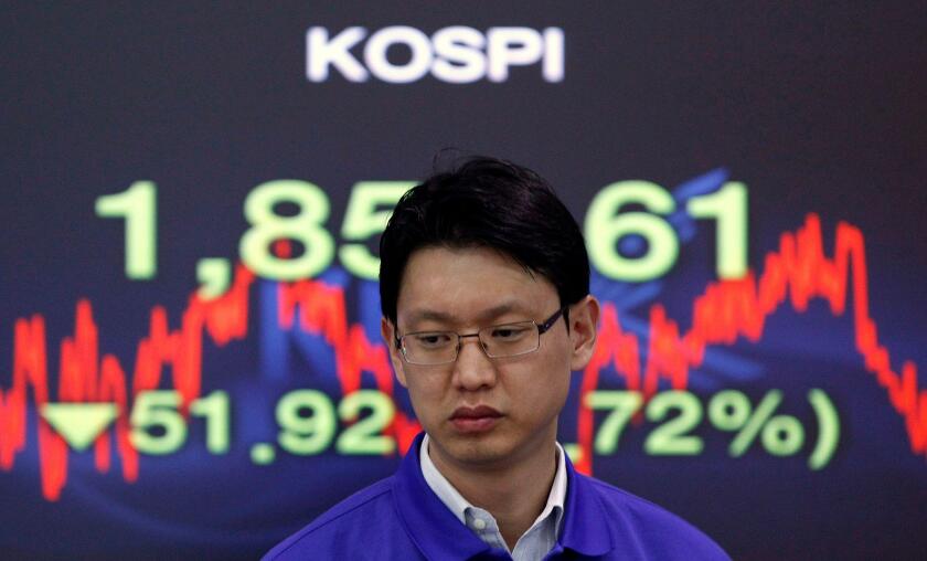 A foreign currency dealer from the Korea Exchange Bank walks past a screen displaying the Korea Composite Stock Price Index (KOSPI) at the bank's dealing room in Seoul November 10, 2011. Seoul shares tumbled on Thursday as a spike in Italian bond yields s
