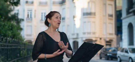 Soprano sings opera on an elegant street with a music stand