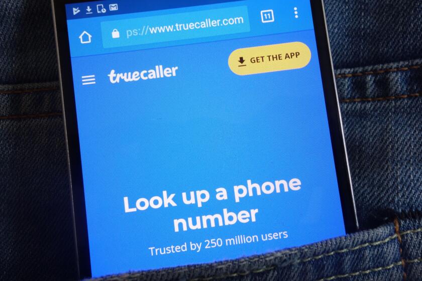 Truecaller website displayed on smartphone hidden in jeans pocket