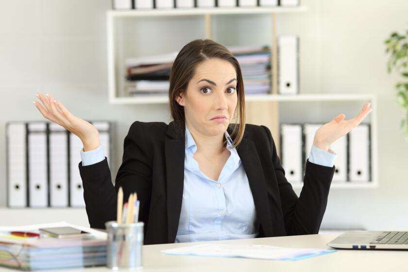 Front view portrait of a confused businesswoman shrugging shoulders looking at camera at office