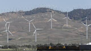 Tehachapi, CA. April 30, 2017. A cargo train passes beneath windmills in the Tehachapi Wind Resource Area, California's largest wind energy farm.
