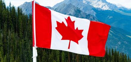 Canadian Maple Leaf national Flag flying over mountains