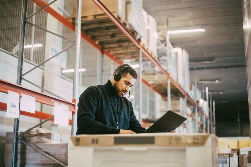 Male manual worker reading document at logistics warehouse