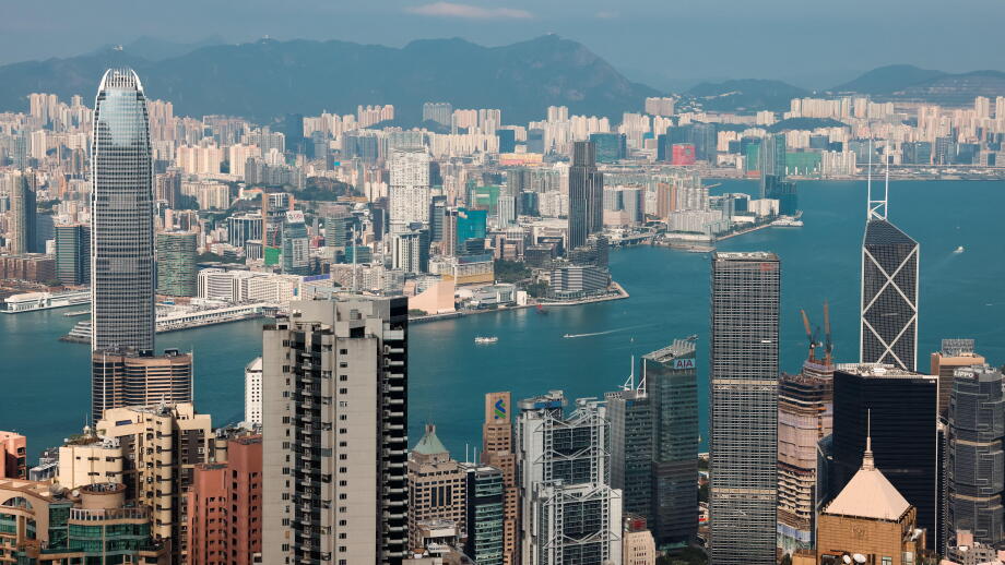 The skyline of Victoria Bay features impressive skyscrapers and busy harbor activities with a clear blue sky above.