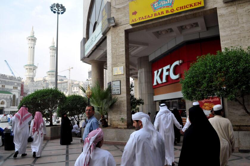 Pilgrims are seen next to 'KFC' (Kentucky Fried Chicken) fast food place located in a shopping mall facing the Great Mosque surrounding the 'kaaba', or the 'Cube', the place towards where hundreds of millions of Muslims around the world pray every day, in