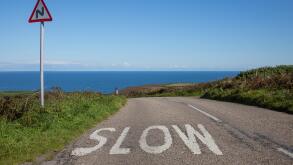 A street to the ocean with a sign and the warning word slow