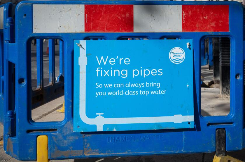A sign next to a hole in the ground from Thames Water supply company stating "We're fixing pipes so we can always bring you world-class water". London
