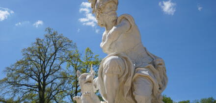 A marble statue of Mars or Ares, the ancient Roman/Greek god of war, with a dog stands in the castle garden park of Sanssouci Palace, Potsdam, Germany