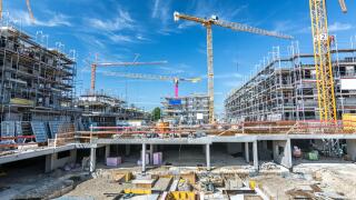 Large construction site with foundations, unfinished buildings and cranes