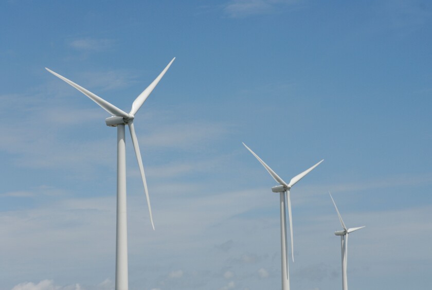Three wind turbines, close-up of blades, against blue sky. Wind power "wind farm" turbines alternative energy, renwable energy.
