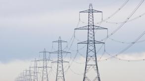 A long straight line of Electricity pylons receding into the distance on Walland Marshes, UK