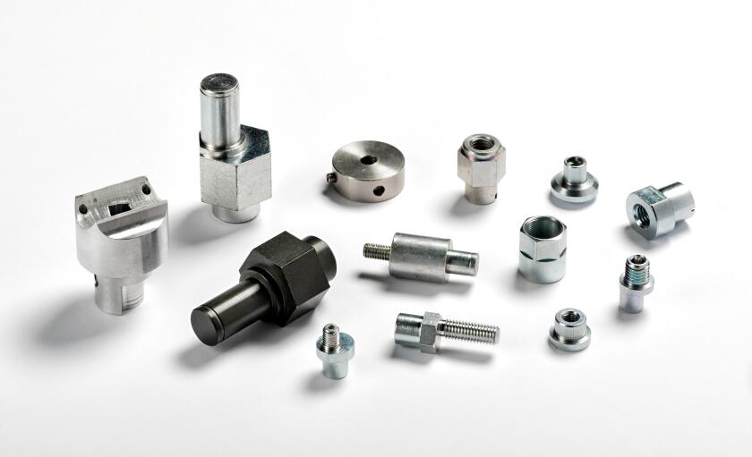 Assorted spare aluminium and iron parts and precision engineered components scattered on a white background with shadows
