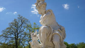 A marble statue of Mars or Ares, the ancient Roman/Greek god of war, with a dog stands in the castle garden park of Sanssouci Palace, Potsdam, Germany