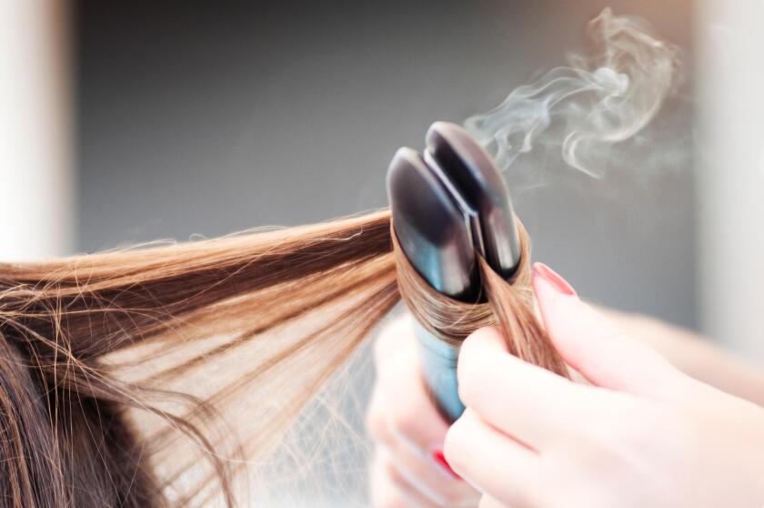 Hairdresser Applying a Straight Iron on a Woman Hairdo