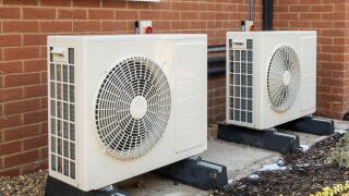 Two air source heat pumps installed on the exterior of a modern house