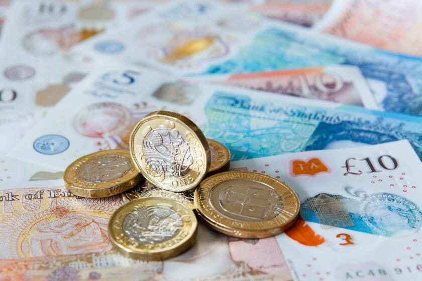 A pile of one pound £ coins British money sterling on new polymer £10 and £5 notes GBP close-up. England UK Britain