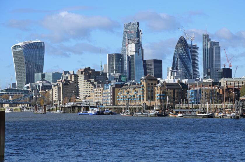 The London City skyline contrasts with warehouses and moored sailing barges on the waterfront in Wapping. Viewed from Bermondsey. UK