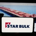 Stuttgart, Germany - 12-16-2025: Person holding cellphone with logo of shipping company Star Bulk Carriers Corp. on screen in front of webpage.