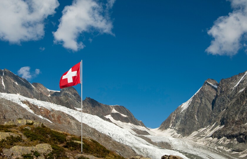 The Swiss flag near the mountain pass Loetschenluecke and the glacier Langgletscher, Loetschental, Valais, Switzerland