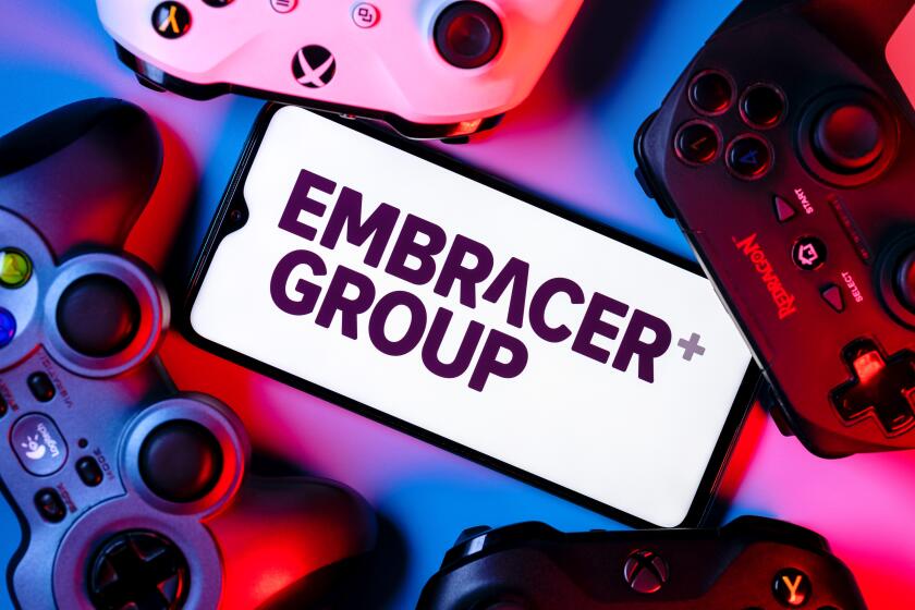 A smartphone with the Embracer Group logo on the screen surrounded by gamepads.