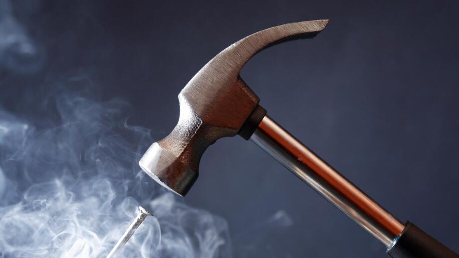 Work tool. Metal hammer above nail with smoke on nice dark background